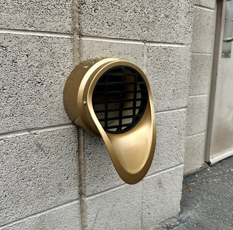 Bronze-finished plastic downspout nozzle with escutcheon ring installed on commercial building